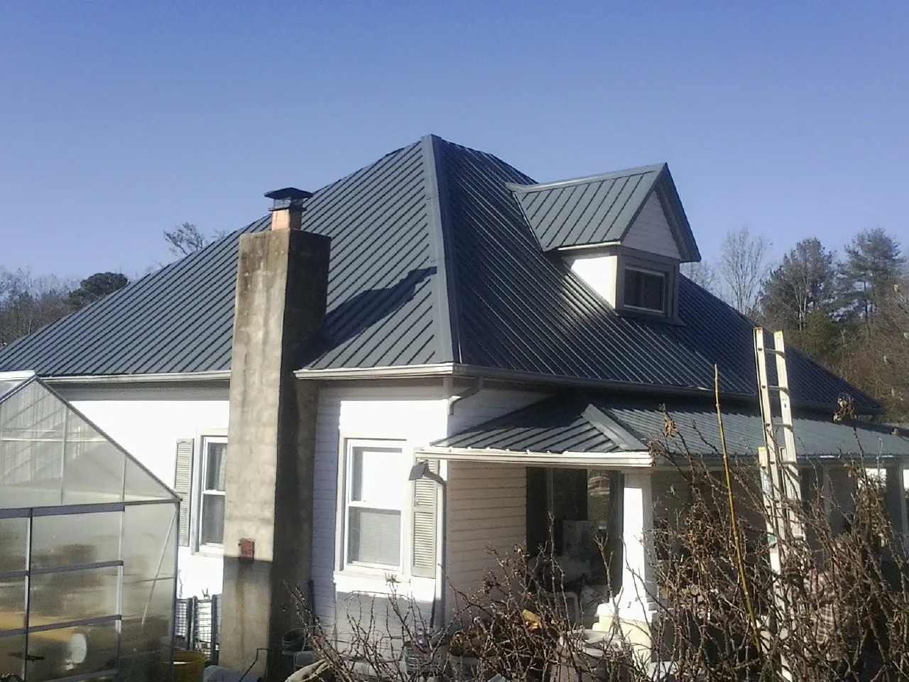 Dark blue standing seam metal roof on a white farmhouse with dormer — Slate & Tile Roof Repair by Roofing Brothers in Camp Grove