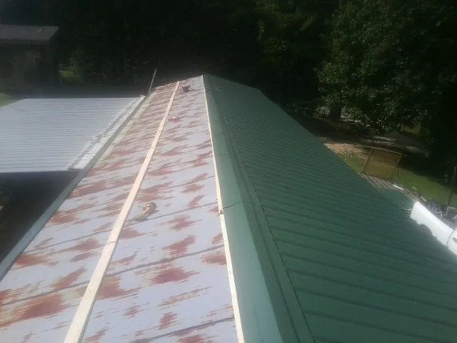 Old rusted panels beside newly installed green metal roofing — Wind Damage Roof Repair by Roofing Brothers in Camp Grove