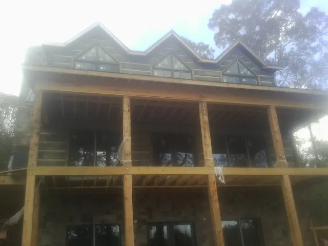 Dormers and porch framing on a large log home under construction — Roof Coating work by our crew in Camp Grove