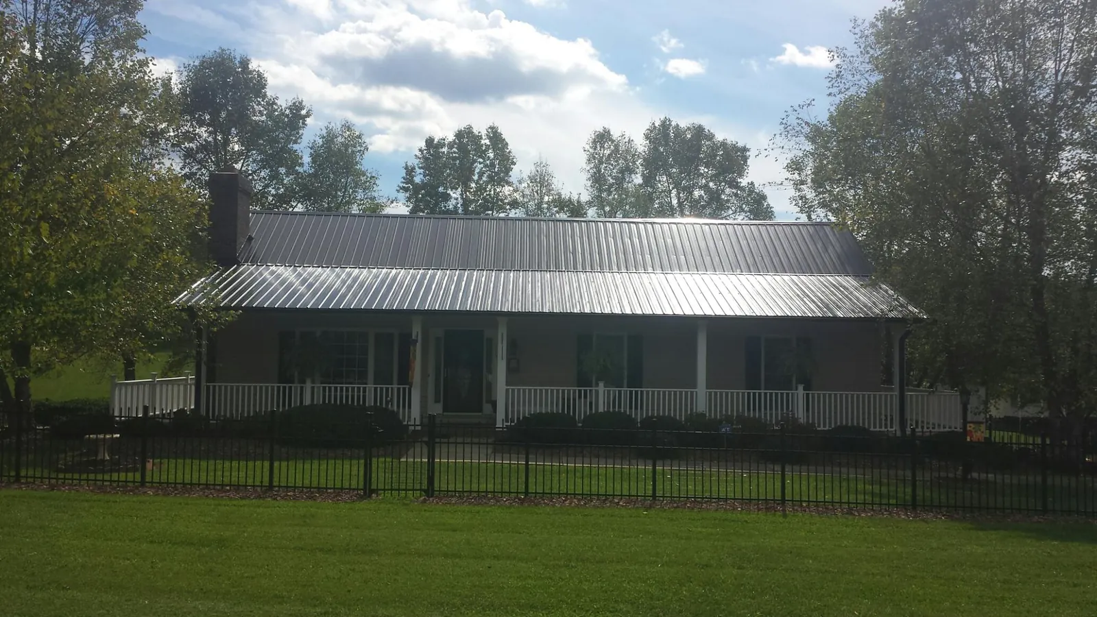 Gray metal roof on a brick ranch with a full width front porch in Camp Grove