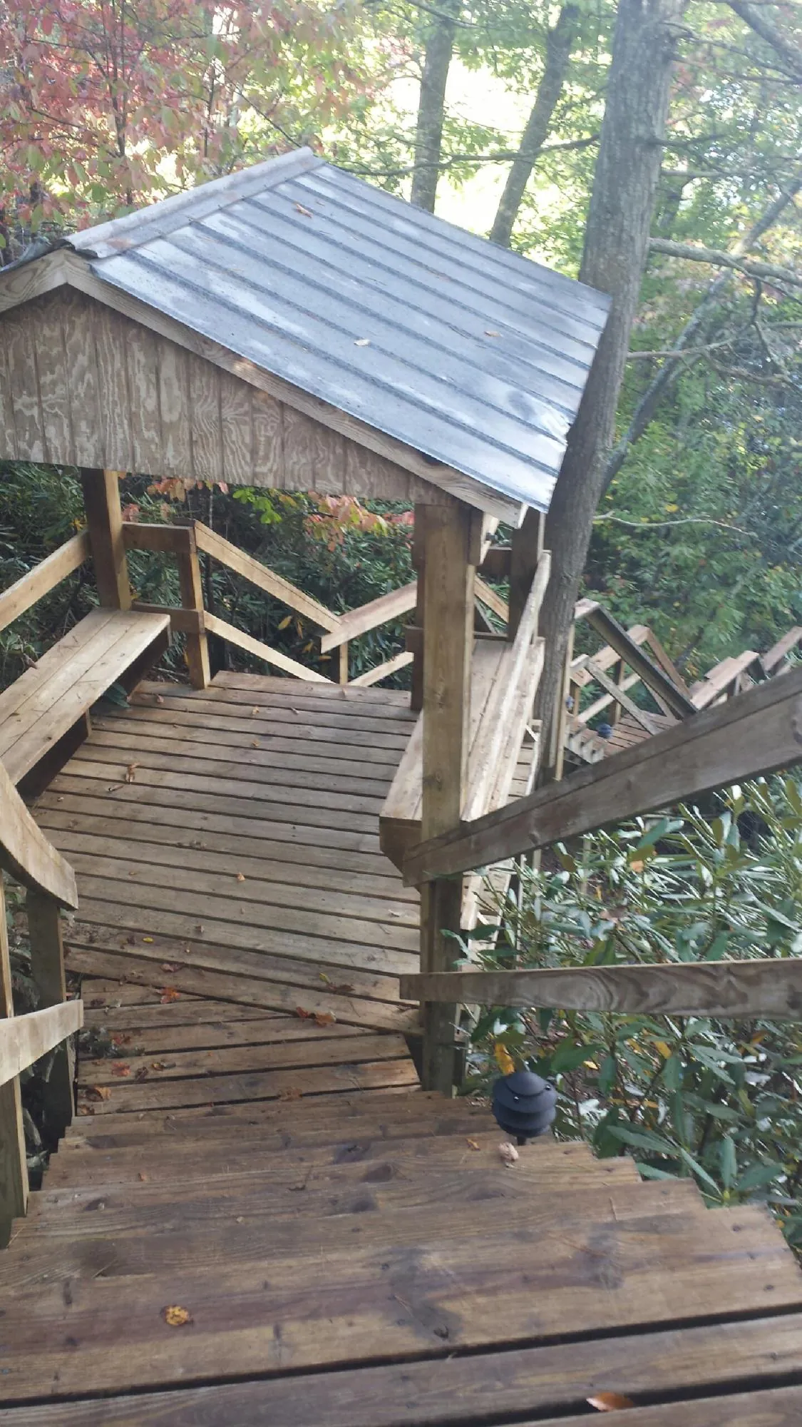 Metal roofed shelter over wooden steps on a wooded walkway — Skylight Repair & Installation work by our crew in Camp Grove