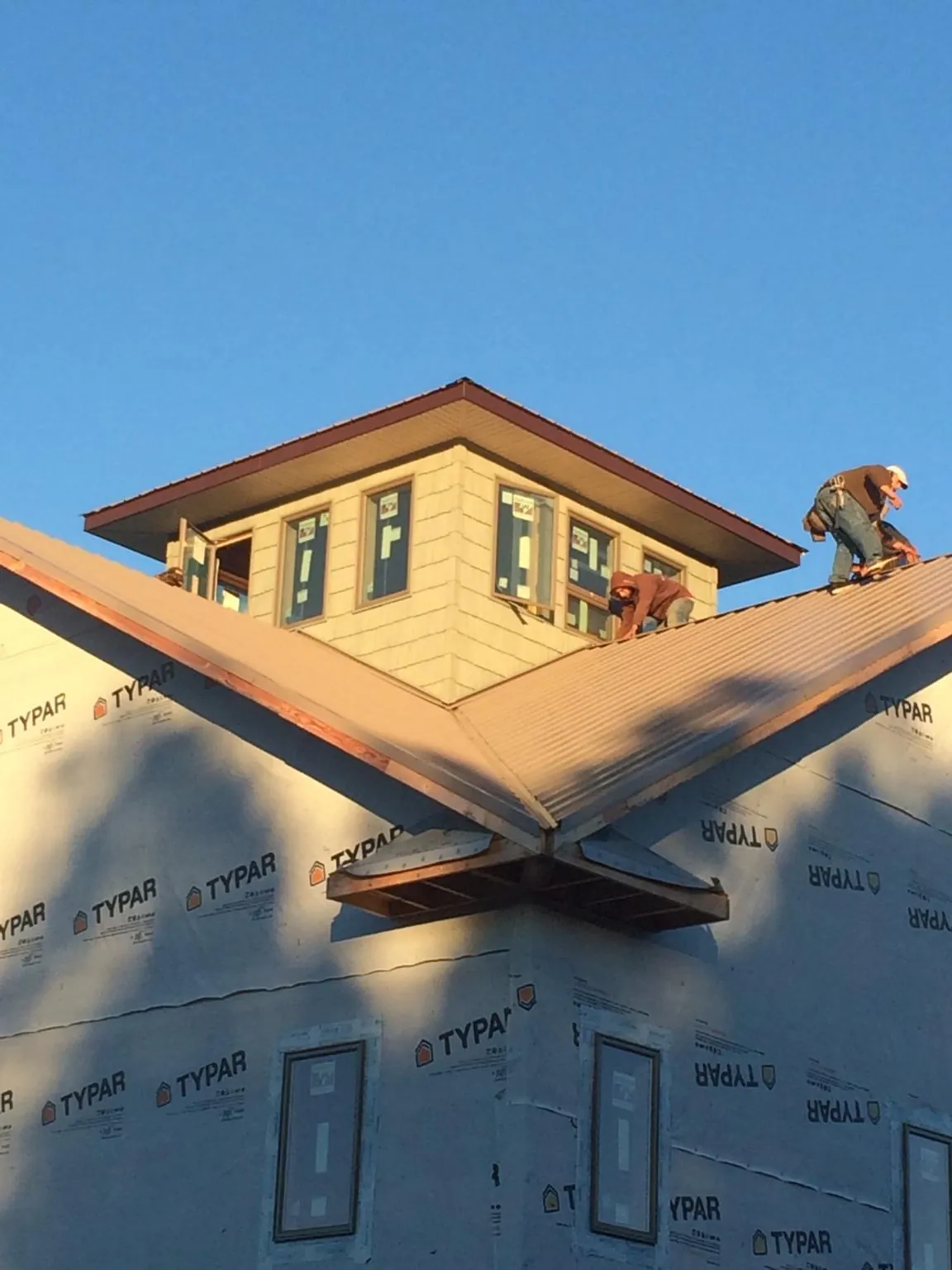 Roofers working around a rooftop cupola on a new metal roof at sunset — Roof Waterproofing in Camp Grove by Roofing Brothers